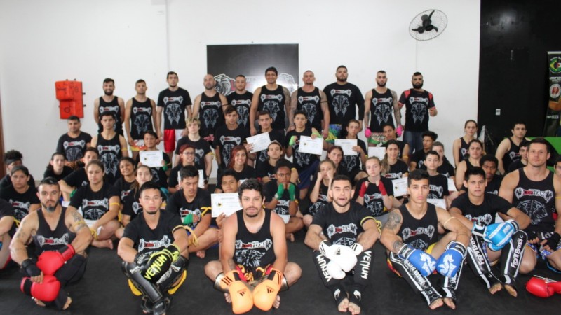 Jovens do CJ Alvorada graduados no Muay Thai pousam para foto com os avaliadores